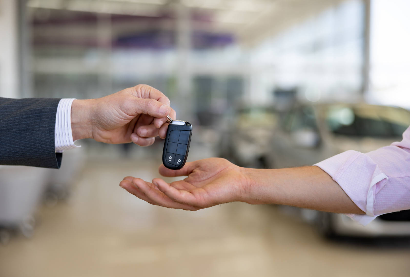 Autoschlüssel wird bei der Fahrzeugübergabe von Hand zu Hand gereicht